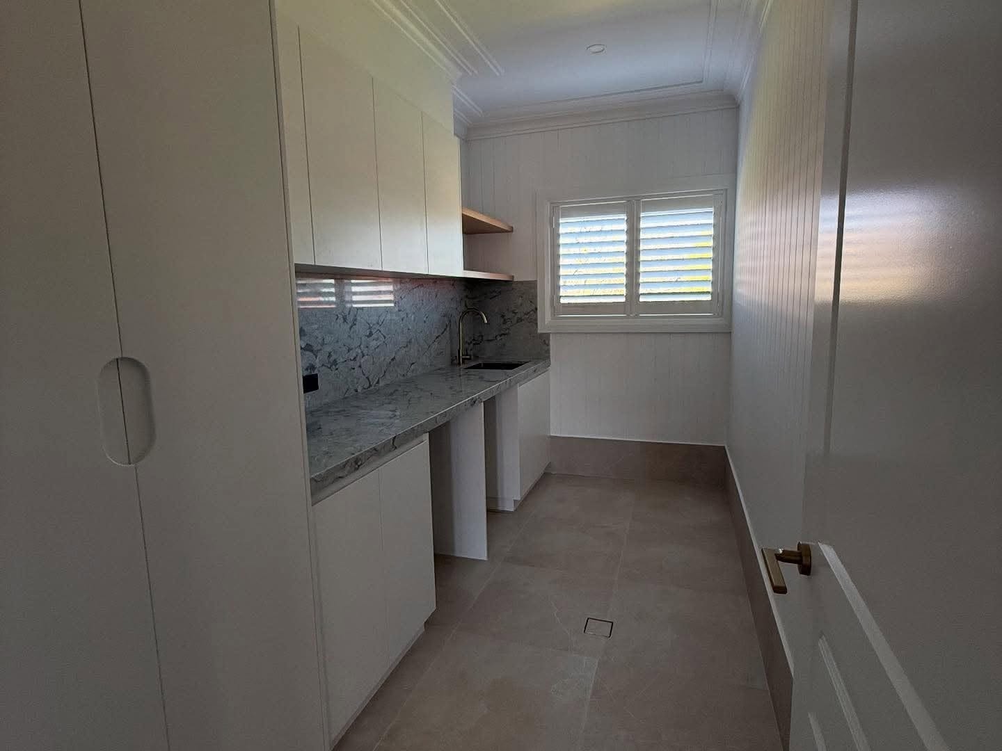 Custom cabinetry and a stone bench in a walk-in pantry by Fabrite Kitchens