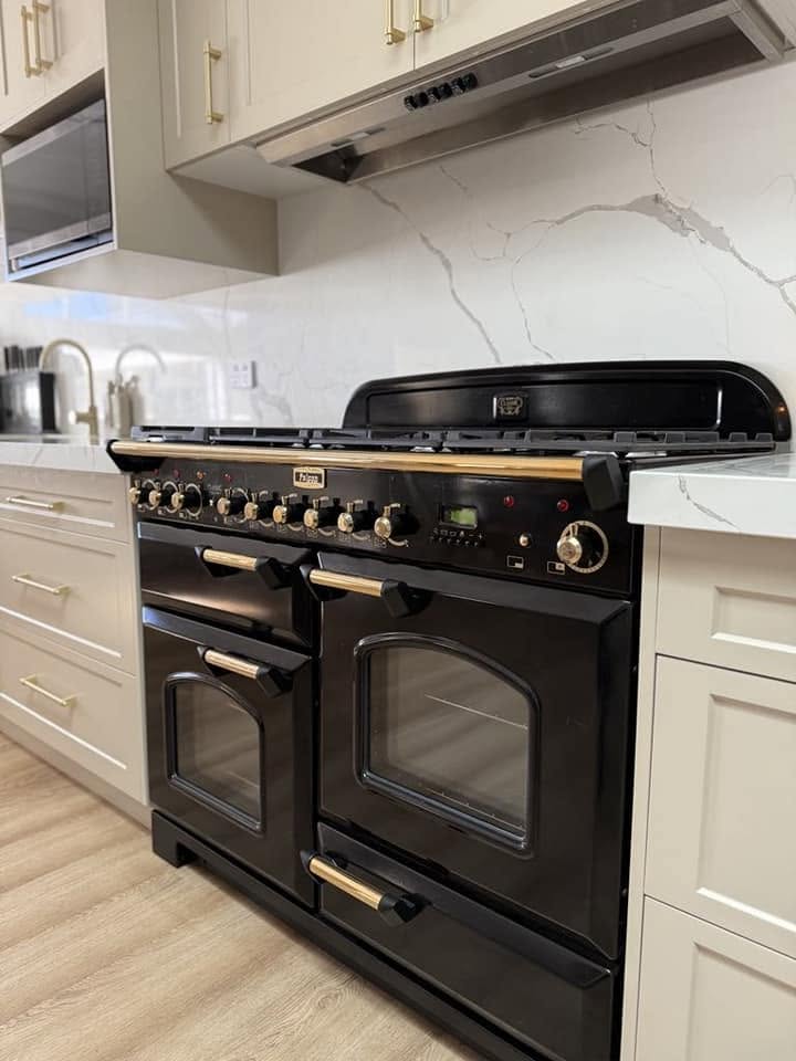 A black range cooker set into white shaker cabinetry, built by Fabrite Kitchens