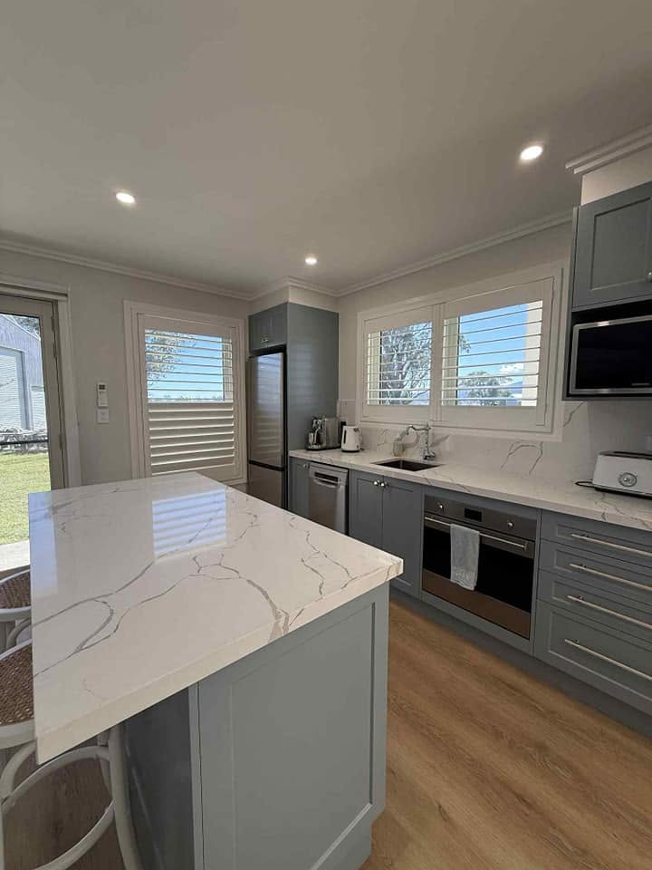 A custom kitchen with a stone island bench and grey cabinetry