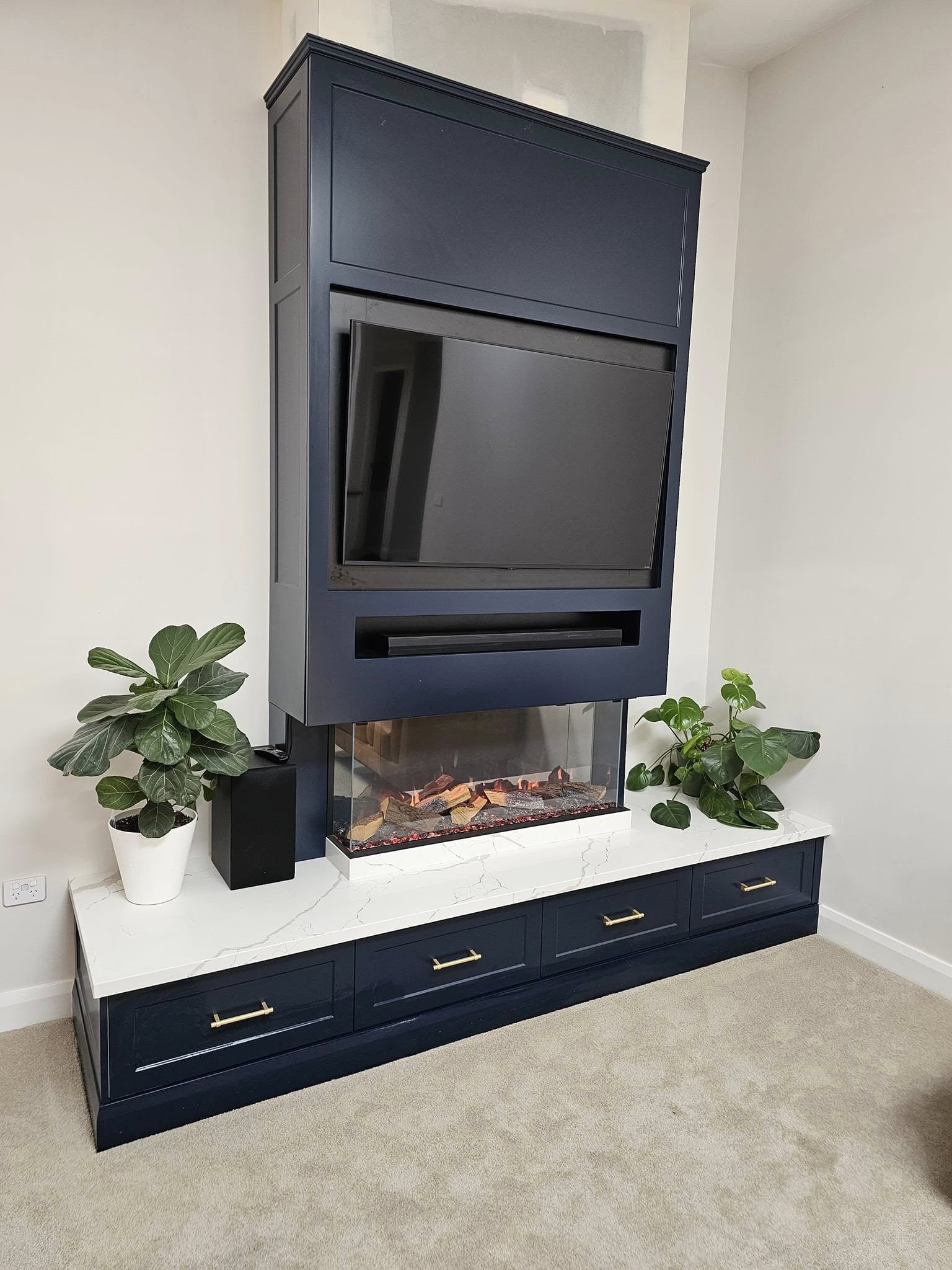 A custom media wall with fireplace and navy cabinetry