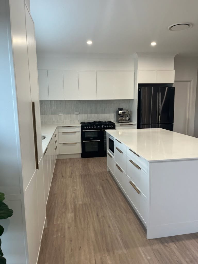 A white custom kitchen island with black appliances