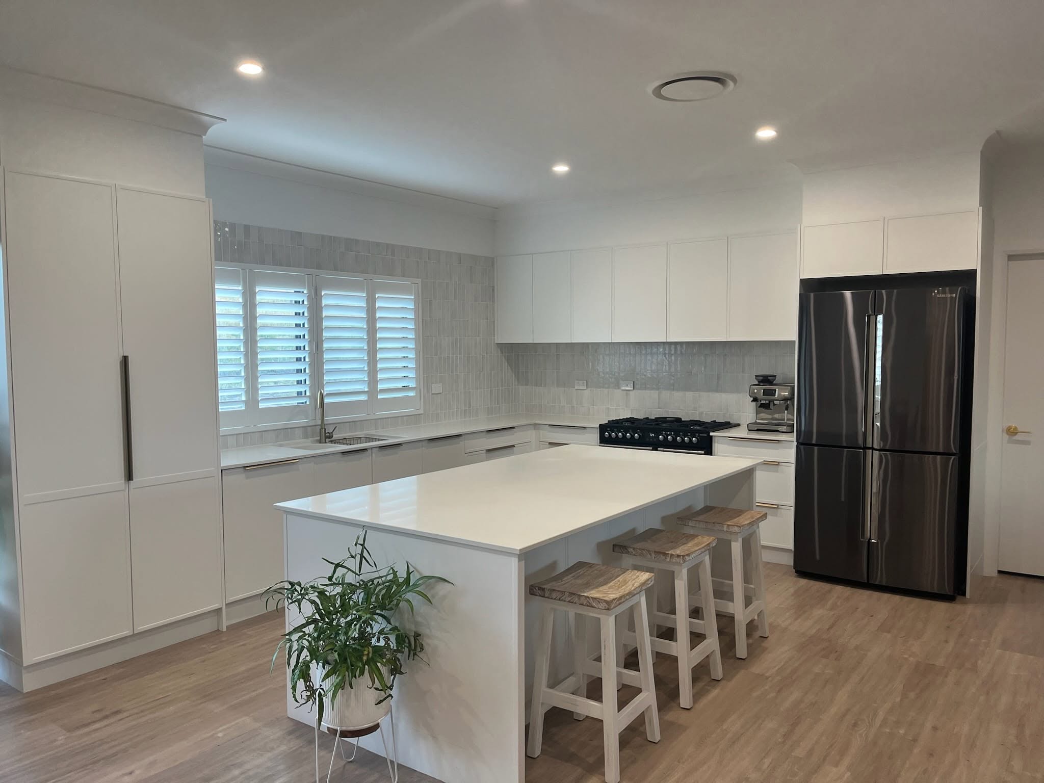 A custom white kitchen with a large stone island bench, built by Fabrite Kitchens in Tamworth