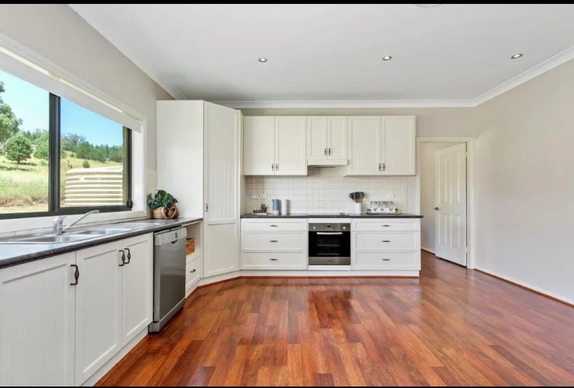 A new white custom kitchen with island bench and timber floors