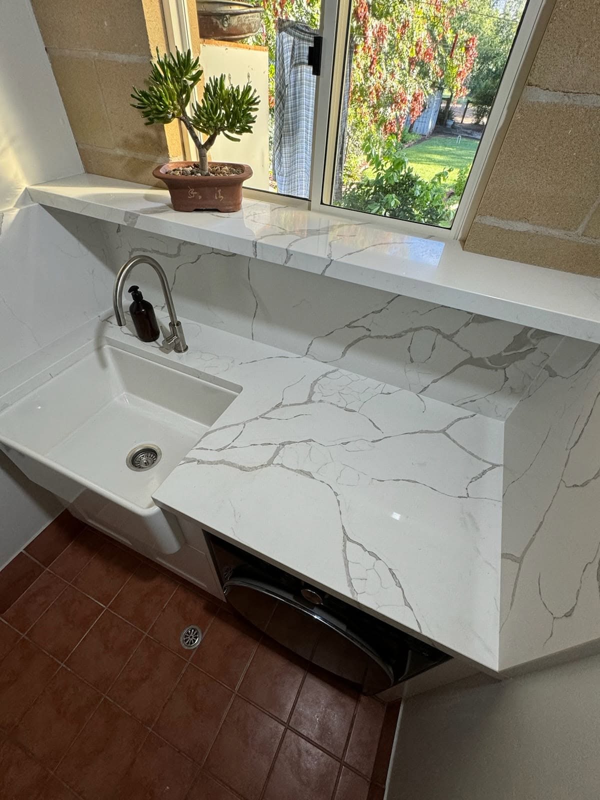 A custom laundry with a stone benchtop and inset sink