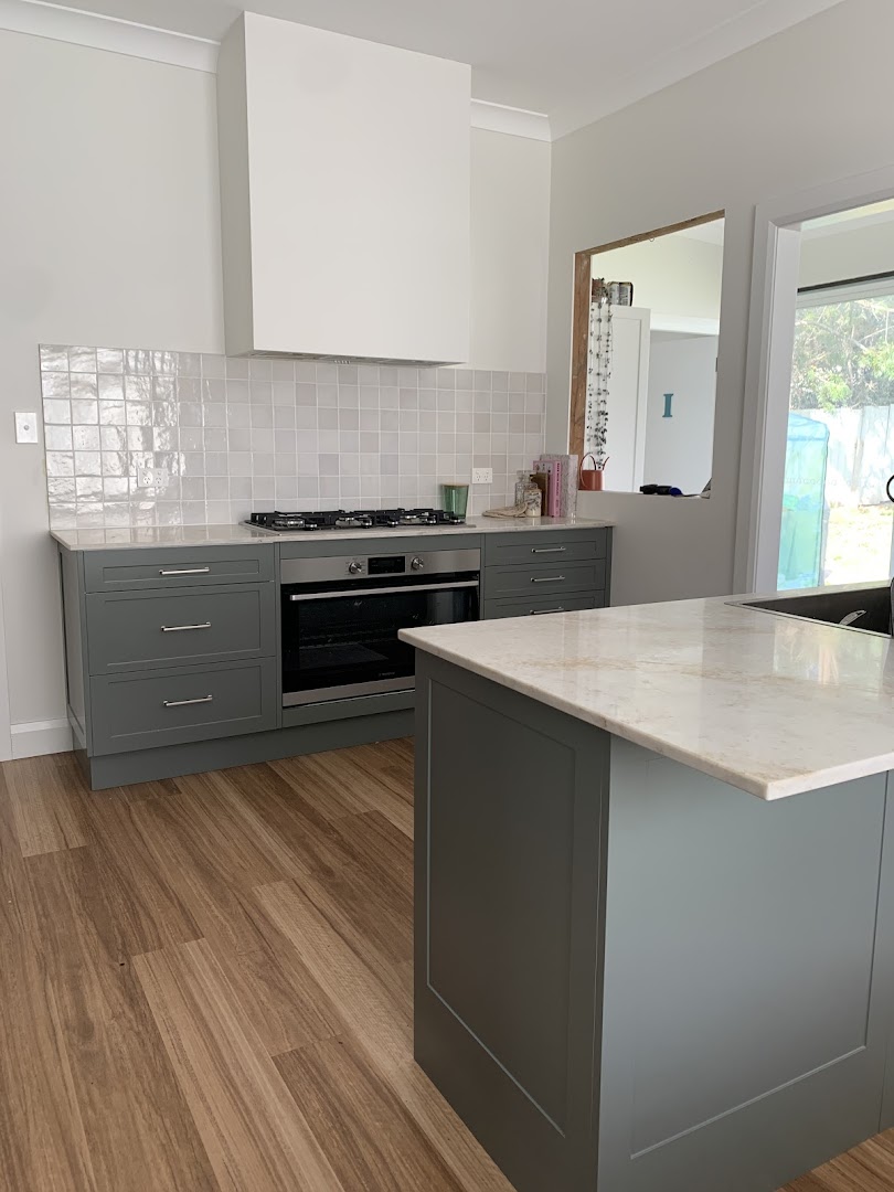 A sage-green custom kitchen with stone benchtops, built by Fabrite Kitchens